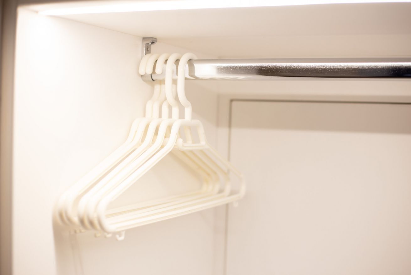 A white towel rack with multiple white hangers.