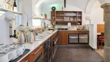 A modern kitchen with stainless steel appliances, a coffee station, and a wine bottle on the counter.