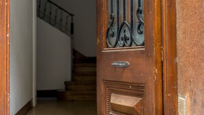 Une porte en bois avec un portail en métal, un escalier en arrière-plan et un mur à la texture particulière.