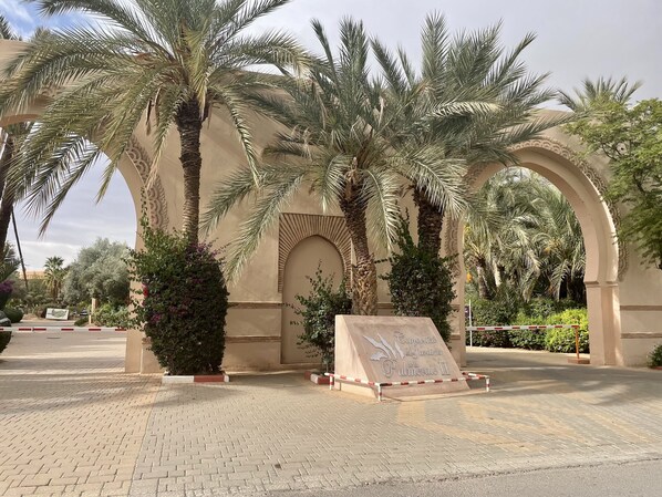 Una entrada pavimentada con palmeras y una estructura en arco.