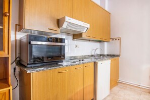 A kitchen with wooden cabinets, a built-in oven, a microwave, a dishwasher, and a stainless steel sink.