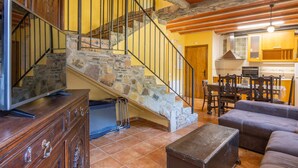 Eine Steintreppe mit Metallgeländer, ein Holzespeisetisch mit Stühlen und eine Ledersofa in einem gut beleuchteten Innenraum.
