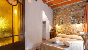 Ein Zimmer mit einem Bett, einer Steinsäule, einem Holzschrank und einem Fenster mit einer rauen Glasscheibe.