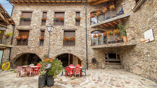 Un bâtiment en pierre doté de balcons, d’une terrasse et de jardinières fleuries.