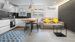 Eine moderne Küche mit Essbereich, einem Sofa mit gelben Kissen und einem kleinen Tisch.