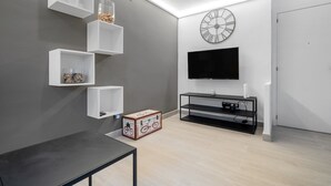 Ein modernes Wohnzimmer mit Flachbildfernseher, weißen Regaleinheiten, einer Holzschatulle und einem minimalistischen Design.