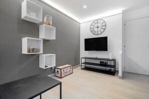 Ein modernes Wohnzimmer mit Flachbildfernseher, weißen Regaleinheiten, einer Holzschatulle und einem minimalistischen Design.