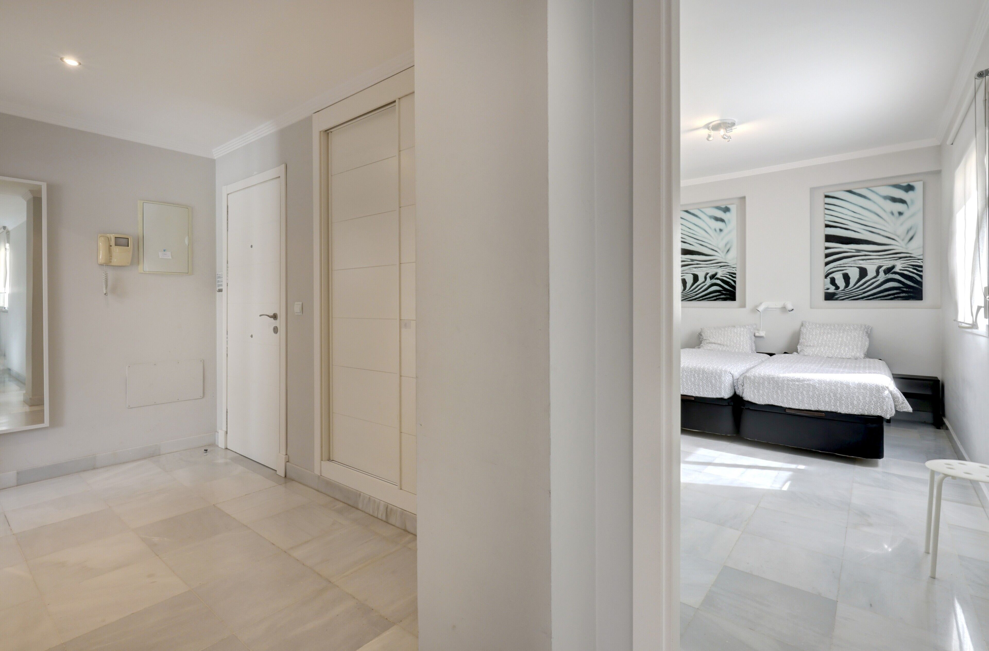 A modern bedroom with a large bed, a bedside table, and a wall-mounted telephone.