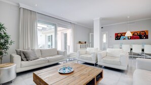 A modern living room with white furniture, a wooden coffee table, and a large painting on the wall. - Apartment "Mirador de la Cala" with Terraces & Wi-Fi (Estepona)