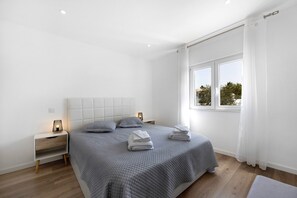 A modern bedroom with a large bed, bedside tables, and a window with curtains.