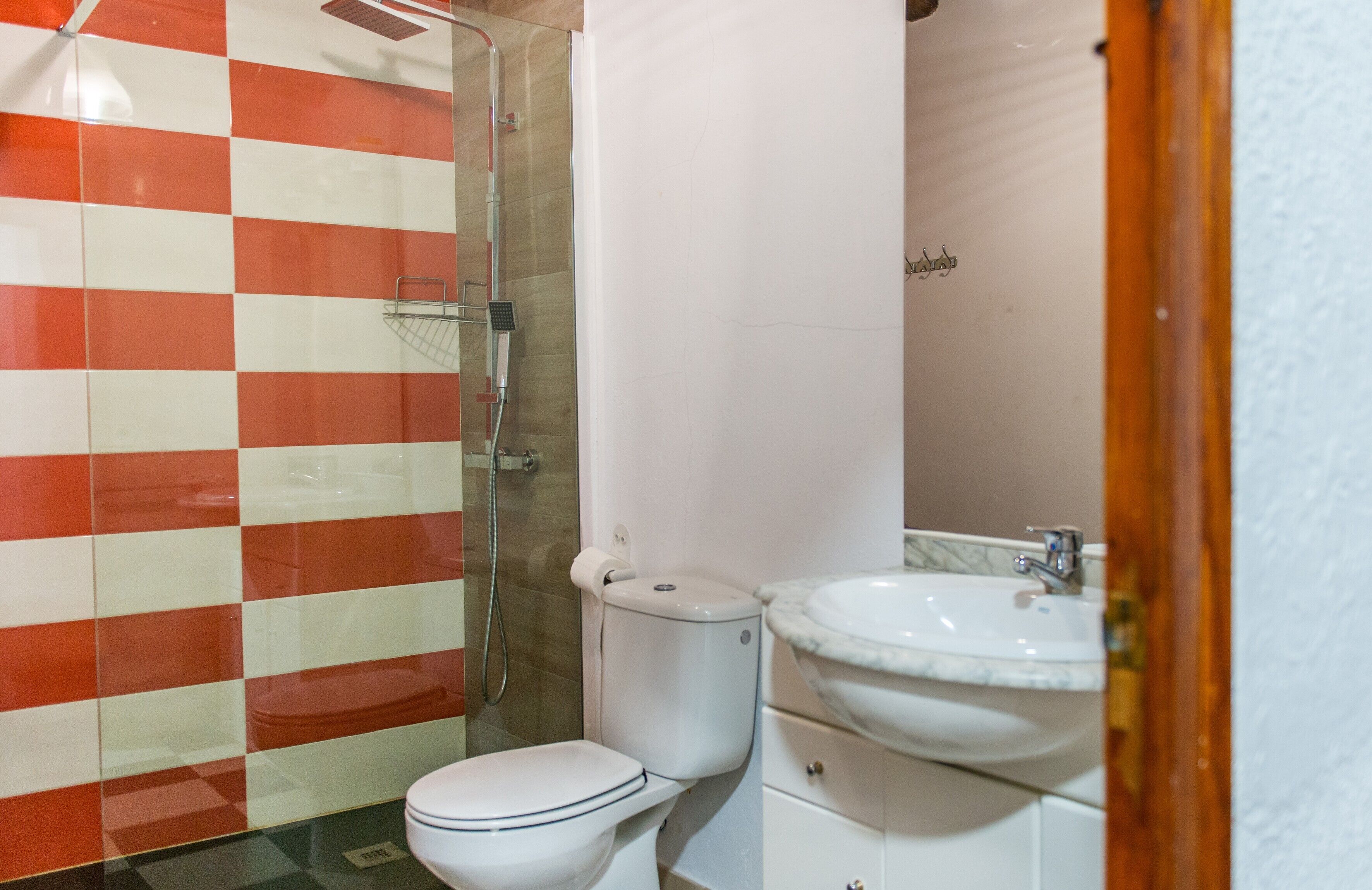 Un baño con pared de baldosas a cuadros, un inodoro, una ducha y un lavamanos.