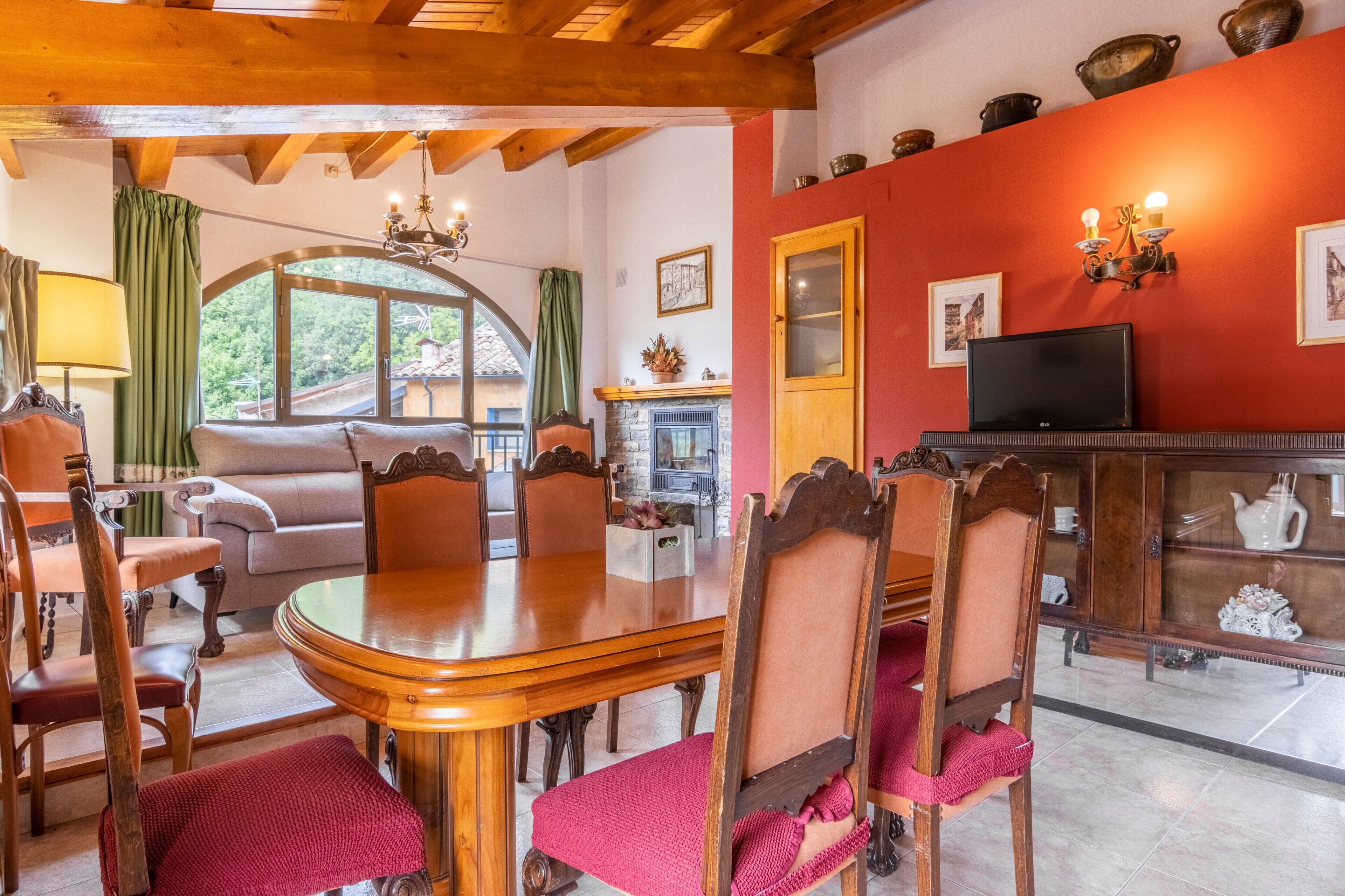A dining area with a wooden table and chairs, a fireplace, and a television on a cabinet.