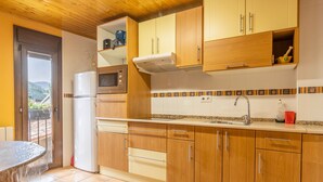A kitchen with wooden cabinets, a microwave, a refrigerator, and a tiled backsplash.