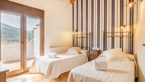 A room with two beds, a view through a sliding door, and a striped wall with wall-mounted lights.