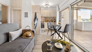 Un salon moderne comprenant un canapé, une table à manger avec des chaises, un coin cuisine et un balcon avec vue.