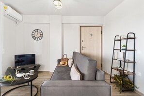 A modern living room with a sofa, a coffee table, a TV, and a bookshelf.
