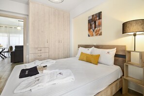 A hotel room with a bed, wooden wardrobe, artwork on the wall, and a lamp. - Holiday Apartment "Evagelia Luxury 2" with Sea View, Shared Pool & Wi-Fi (Nikiana)