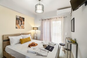 A hotel room with a bed, a desk, a lamp, a painting, and a TV.