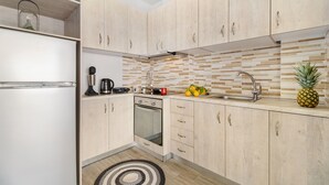 Une cuisine moderne avec des meubles en bois clair, un four encastré, un évier en acier inoxydable et un tapis à motifs noir et blanc.