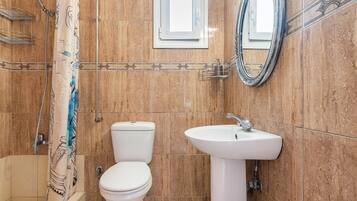 Un baño con ducha, inodoro, lavamanos y espejo.