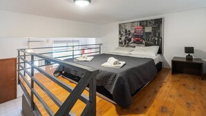 A bedroom with a bunk bed, a bed with a dark blanket, a poster on the wall, a nightstand, and a wooden floor. - Apartment 'Rafaela's House' with Shared Pool, Wi-Fi and Air Conditioning (Koskinou)