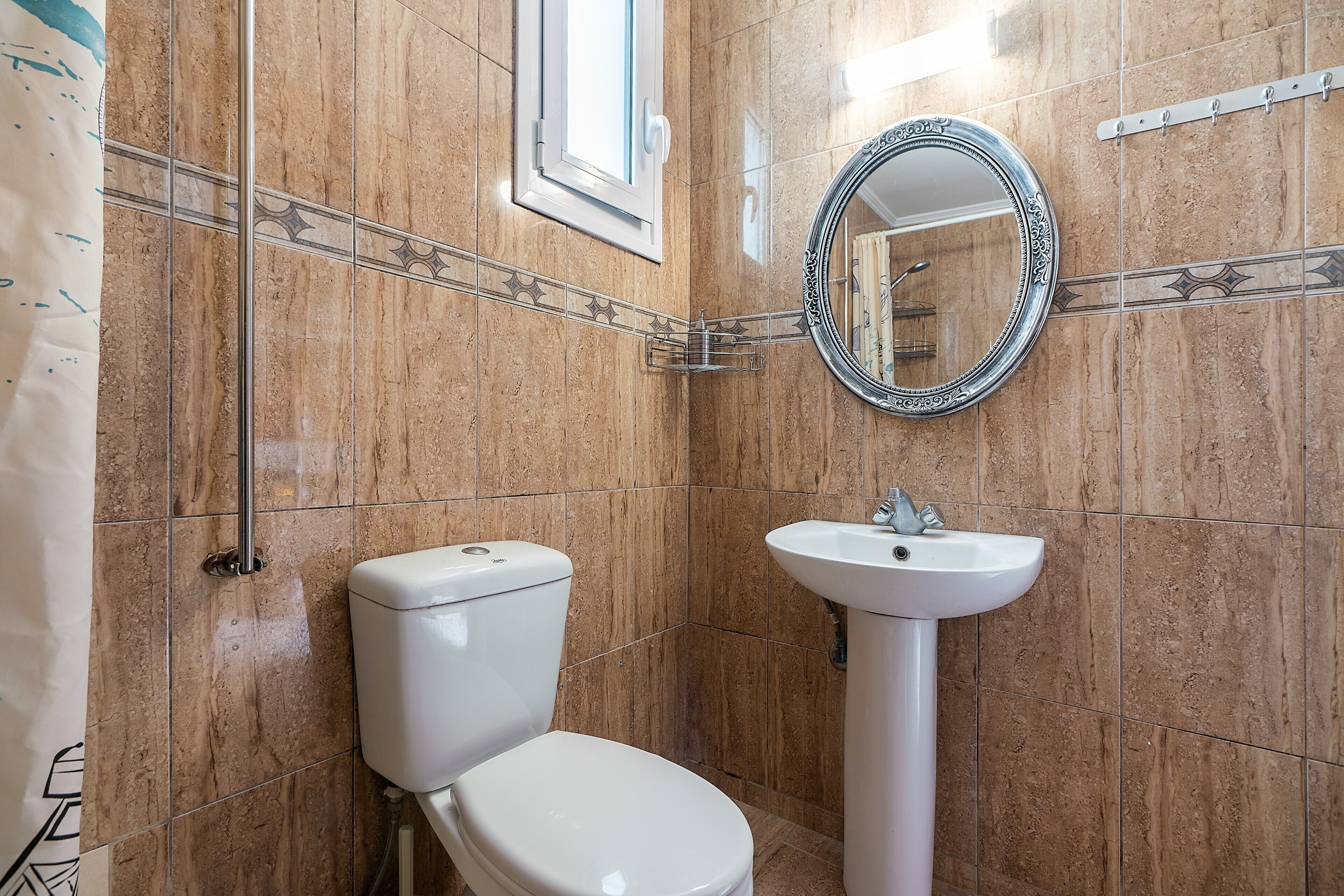A bathroom with a toilet, sink, and a mirror.