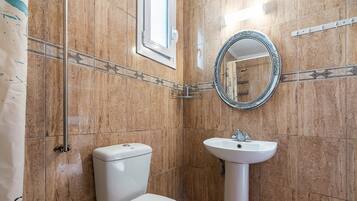 A bathroom with a toilet, sink, and a mirror.