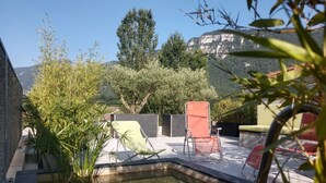 A pool area with chairs and a small water feature, surrounded by greenery and a mountain backdrop. - Vacation Home with Mountain View in the Vercors National Park (IZERON)
