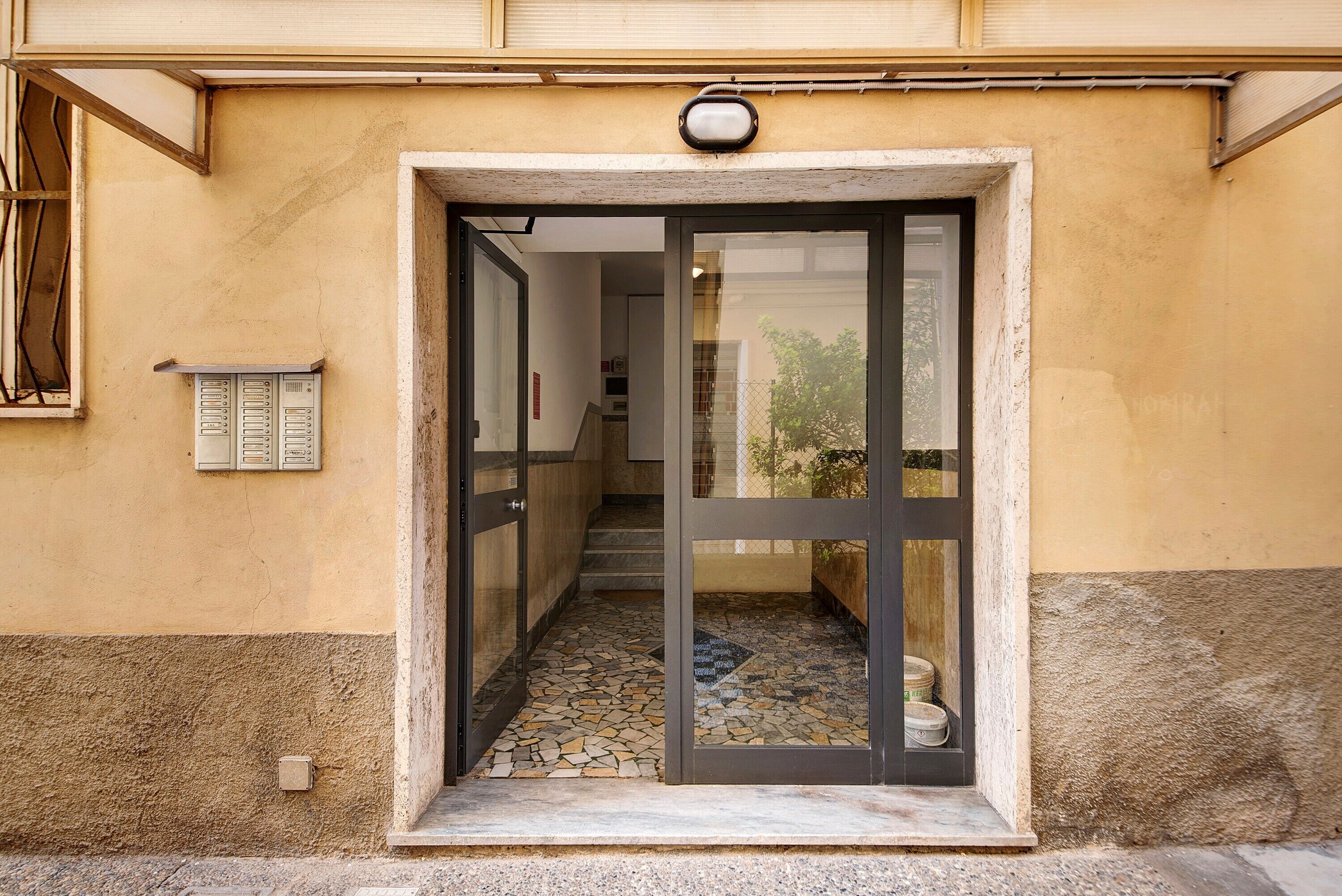 A building entrance with a tiled pathway leading to a door.