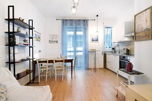 A compact living space with a dining area, kitchenette, and a bookshelf.