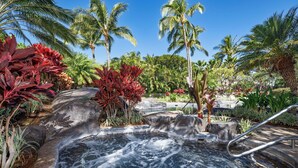 A hot spring surrounded by tropical plants and palm trees.