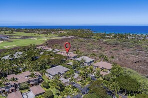 Vista aérea de una zona residencial con casas, palmeras y un campo de golf.