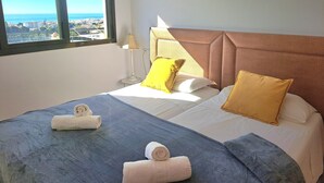 A hotel room with a bed, pillows, a lamp, a window with a view, and towels. - Holiday Apartment "Paraíso Azul" with Sea View, Shared Pool (Summer) & A/C (Nerja)