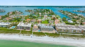 An aerial view of a coastal residential area with buildings, a beach, and a marina.