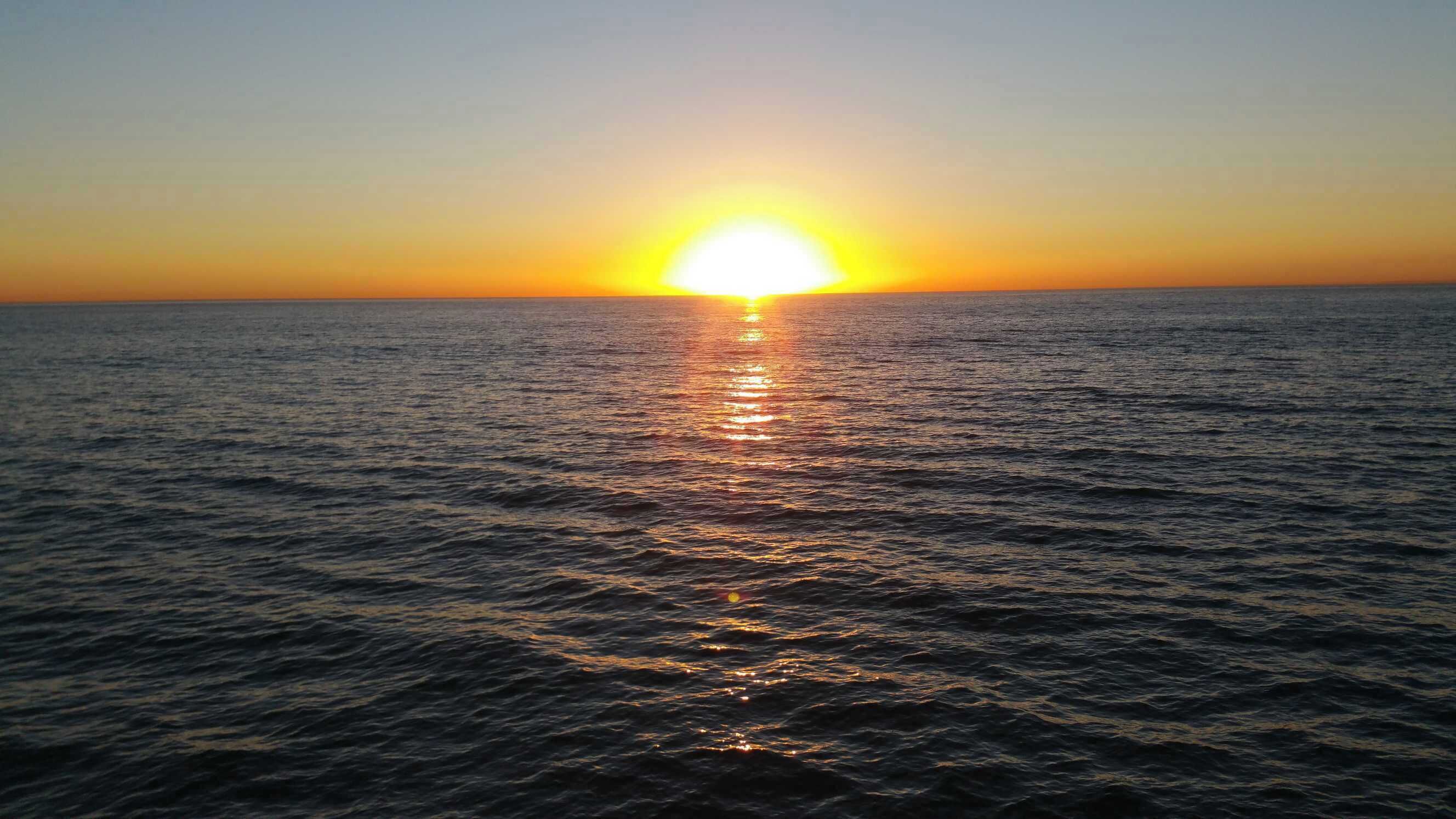 A sunset over a calm sea with no visible land or structures.