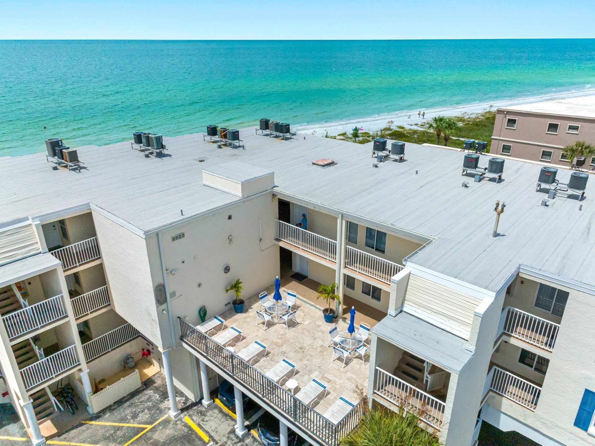 A multi-story hotel with a rooftop terrace featuring outdoor seating and air conditioning units.