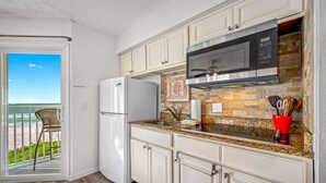 A kitchen with a refrigerator, microwave, and granite countertop.