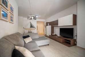 Relax in this stylish living room with a large sofa, flat-screen TV, and refrigerator.