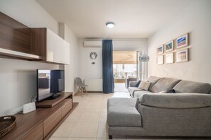 Relax in this stylish living room with a flat-screen TV, comfortable sofa, and ample storage.