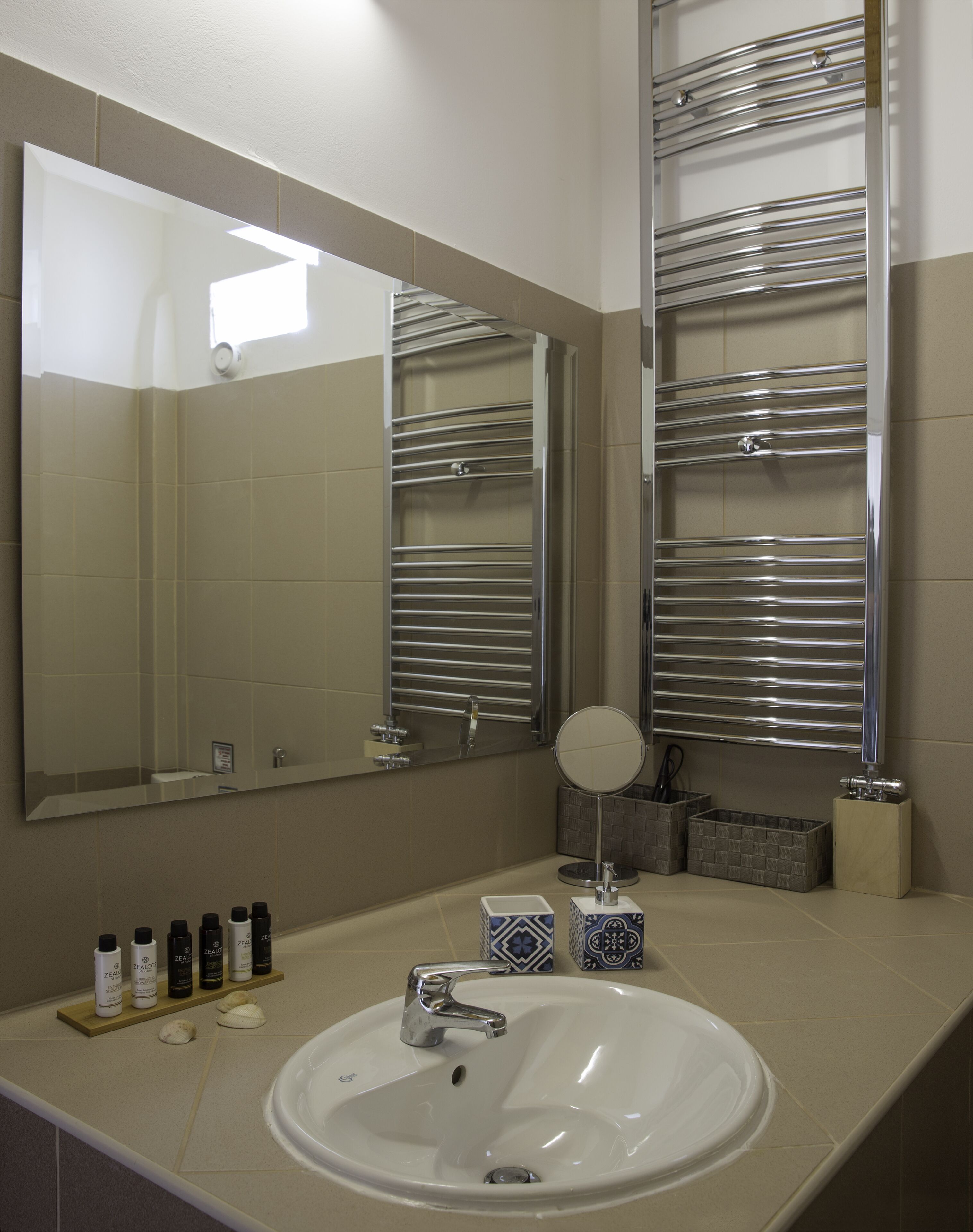 A bathroom with a white sink, a mirror, and two towel racks.