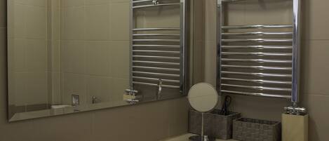 A bathroom with a white sink, a mirror, and two towel racks.