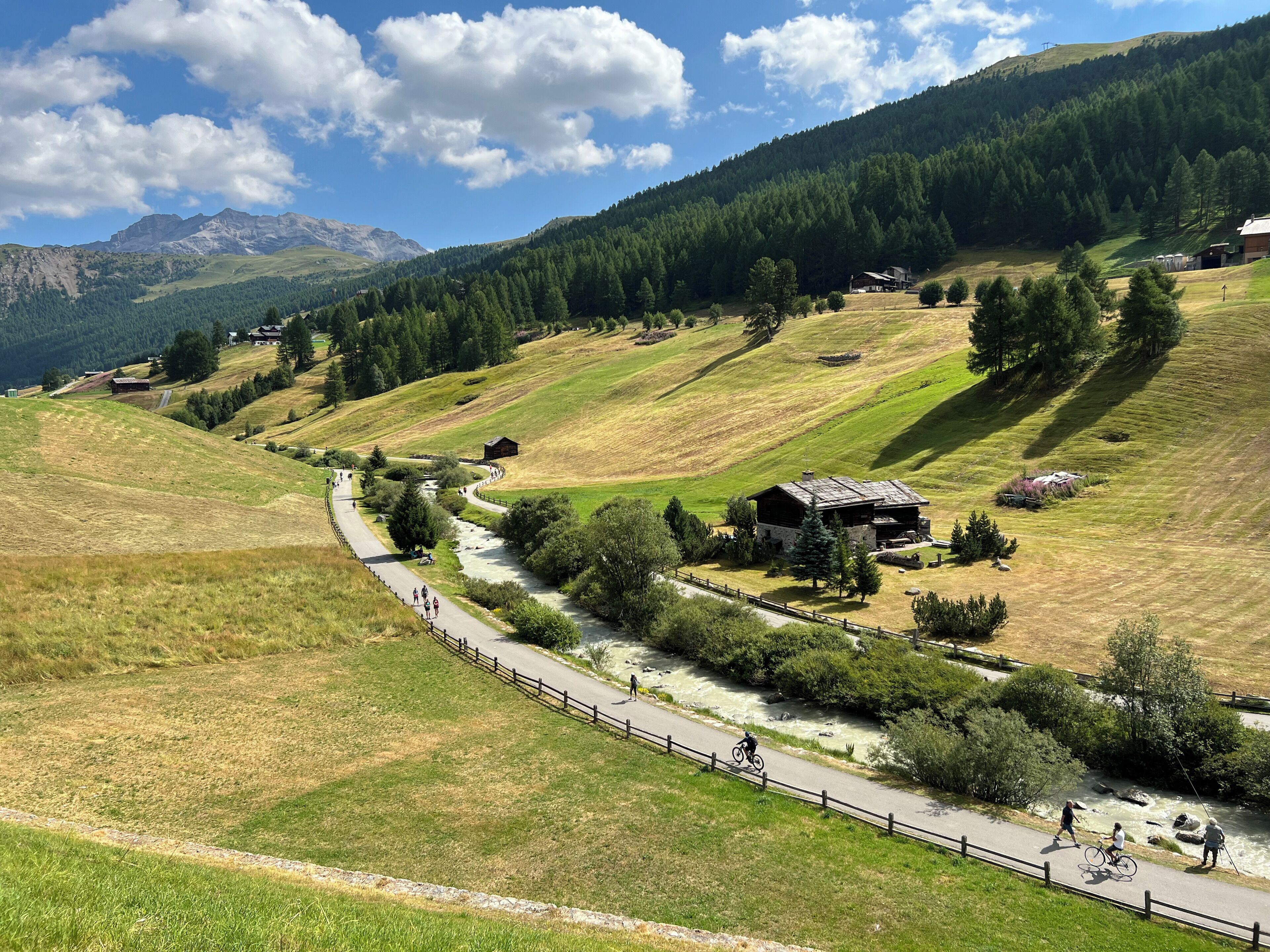 A rural landscape with a winding road, a small wooden house, and a river.
