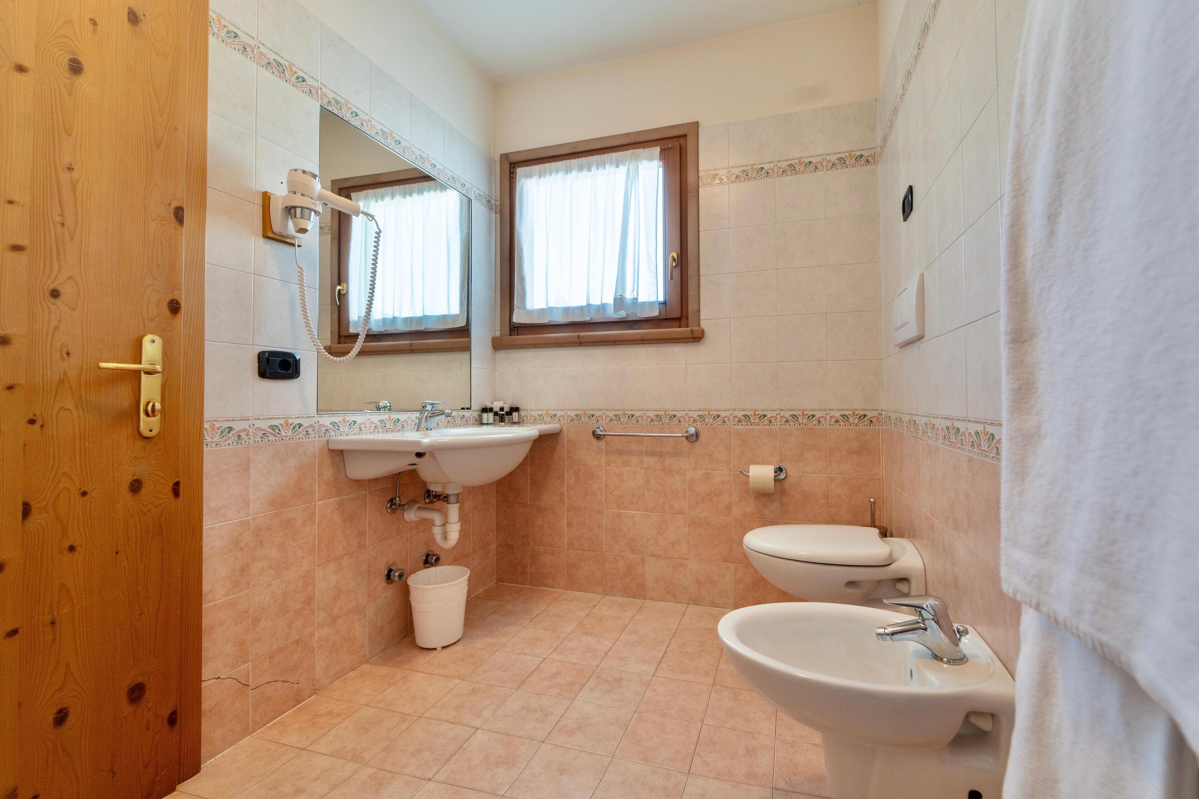 Un baño con puerta de madera, lavamanos, inodoro y bidé.