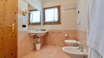 Un baño con puerta de madera, lavamanos, inodoro y bidé.