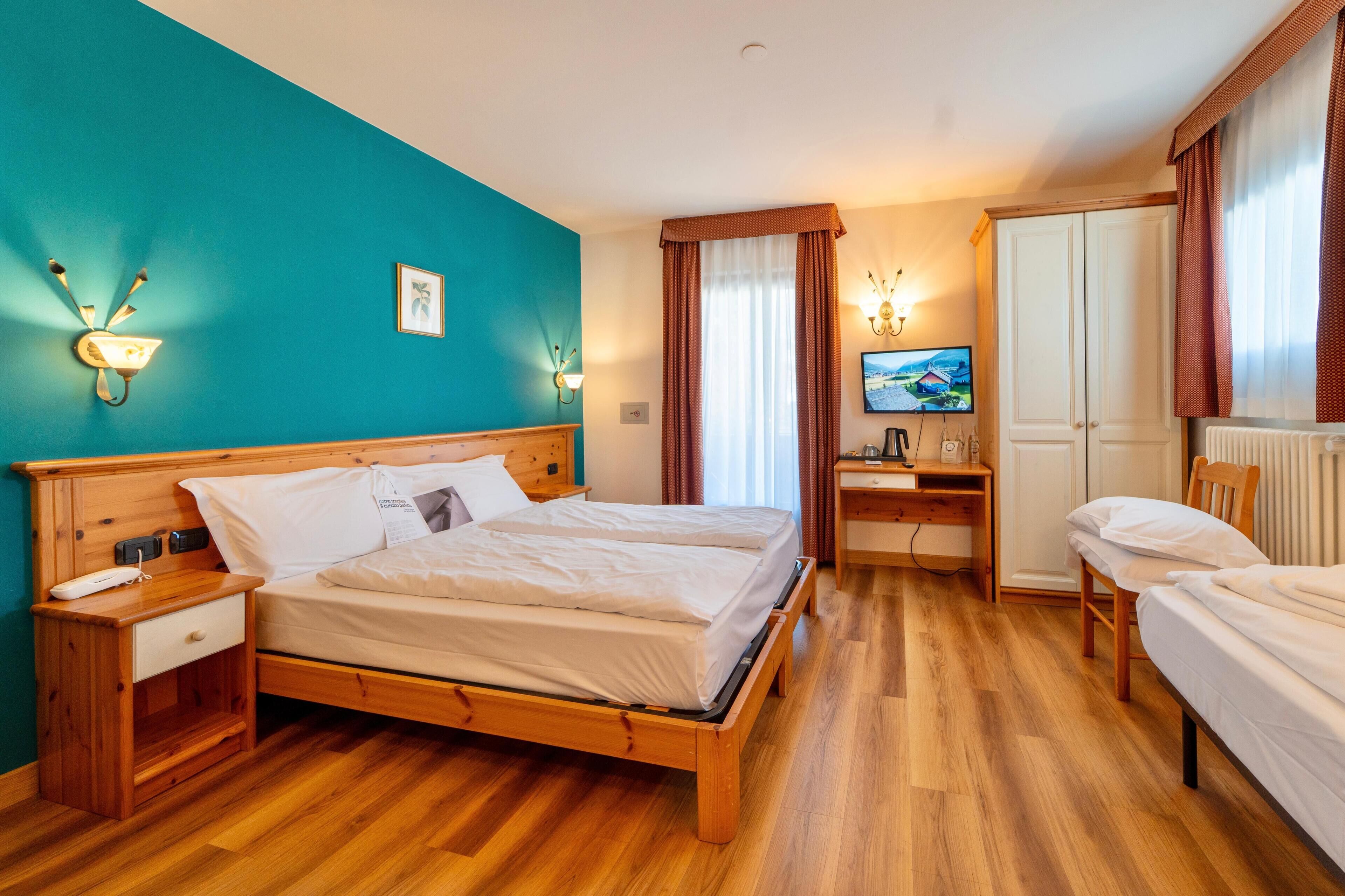 Una habitación de hotel con una cama de madera, un escritorio con una silla, un televisor y un armario.