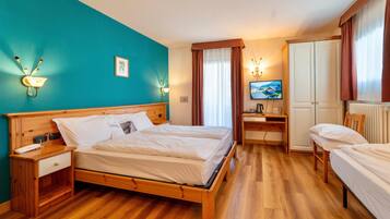 Una habitación de hotel con una cama de madera, un escritorio con una silla, un televisor y un armario.