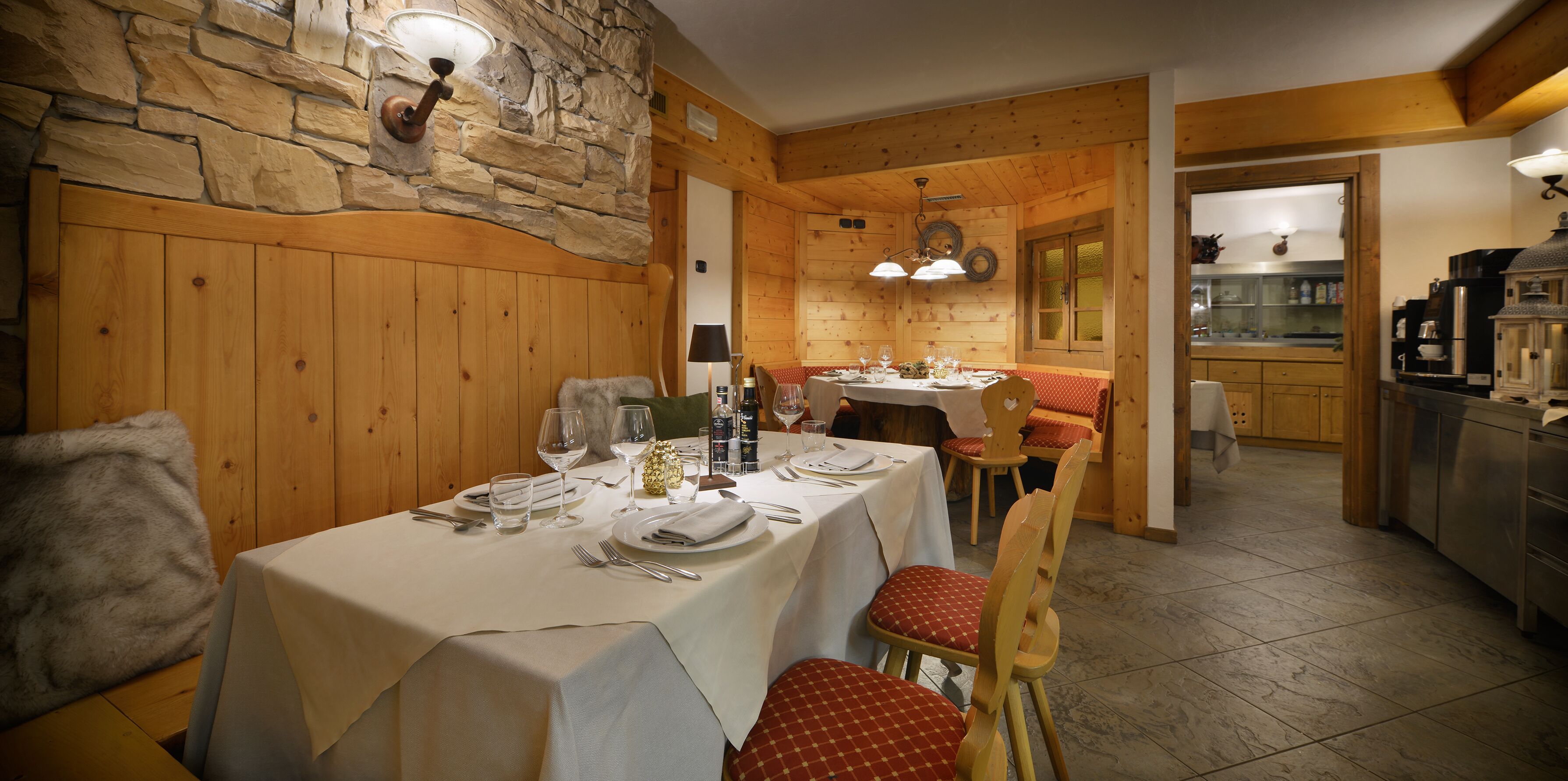 Un interior de madera con una mesa de comedor para cuatro personas, una zona de cocina y una acogedora disposición de asientos.