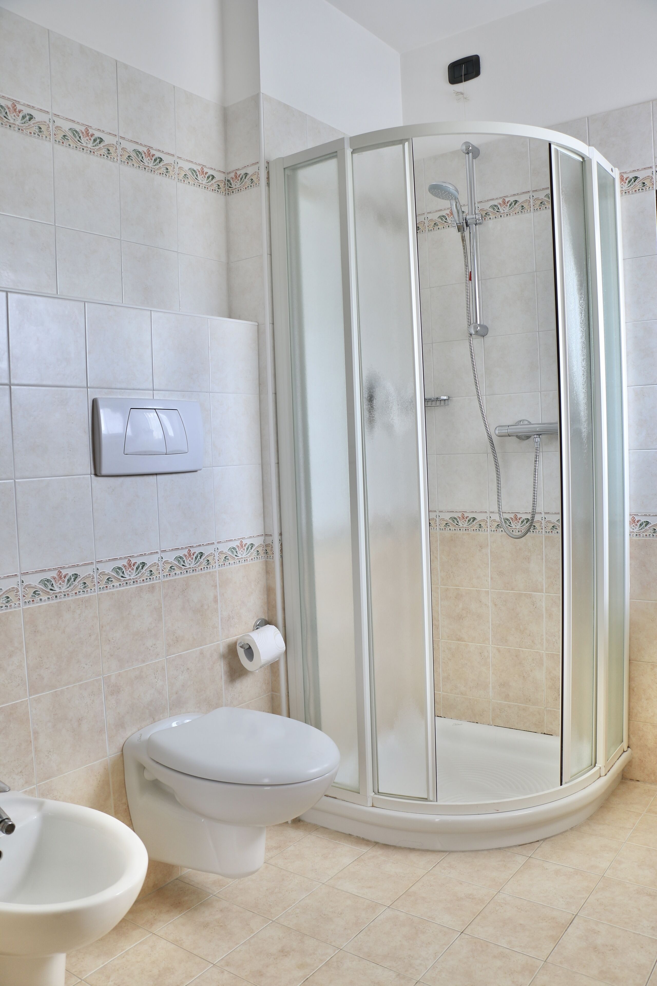 A bathroom with a glass-enclosed shower, a toilet, and a sink.