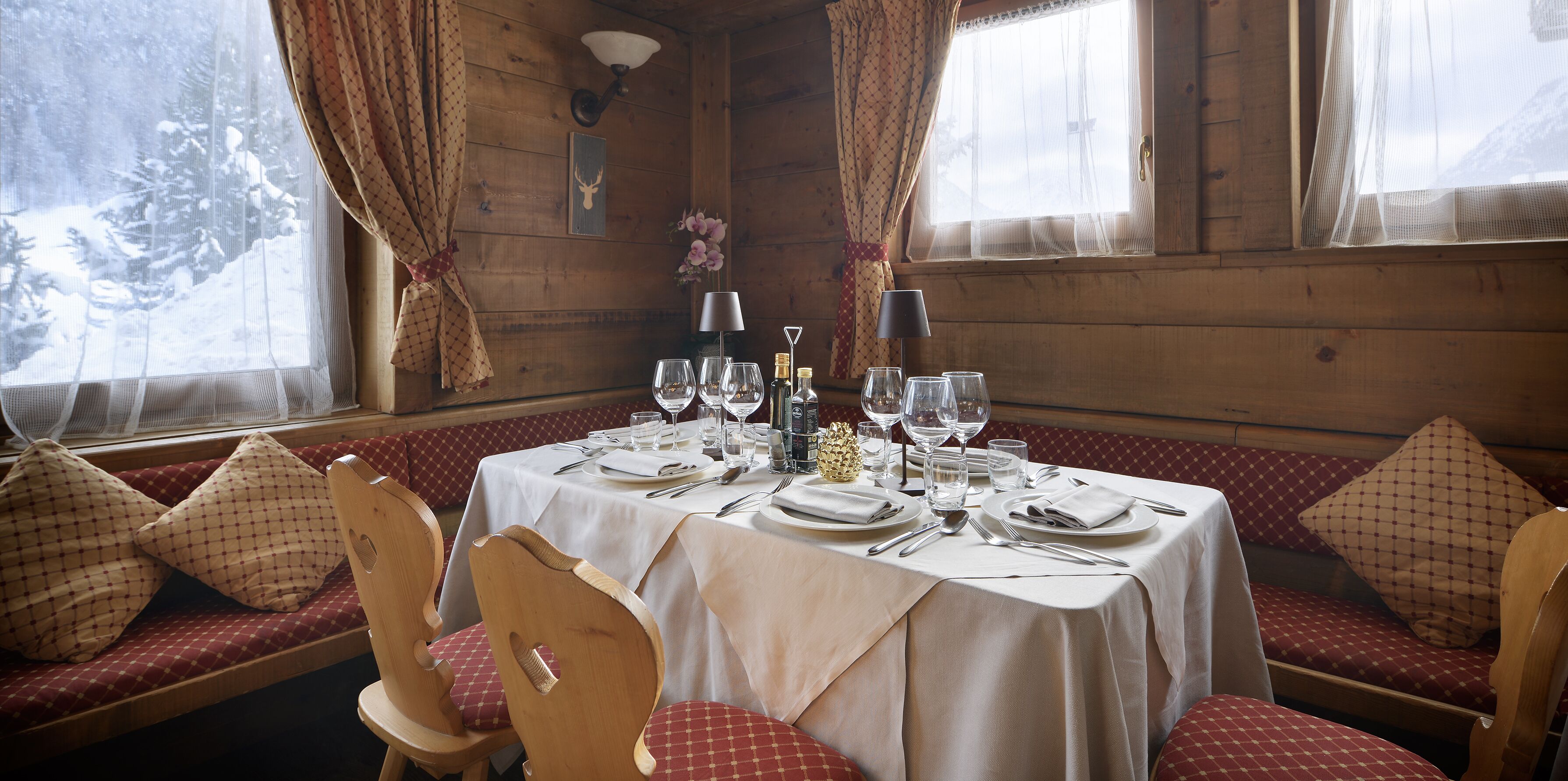 Un comedor acogedor de estilo cabaña con interior de madera, una mesa dispuesta para cuatro personas y una zona de estar con banco.
