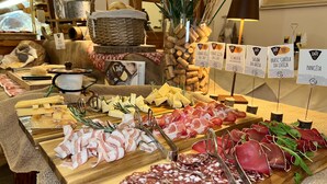 A variety of cheeses, cured meats, and wine corks displayed on a wooden board. - Hotel Primula (Livigno)